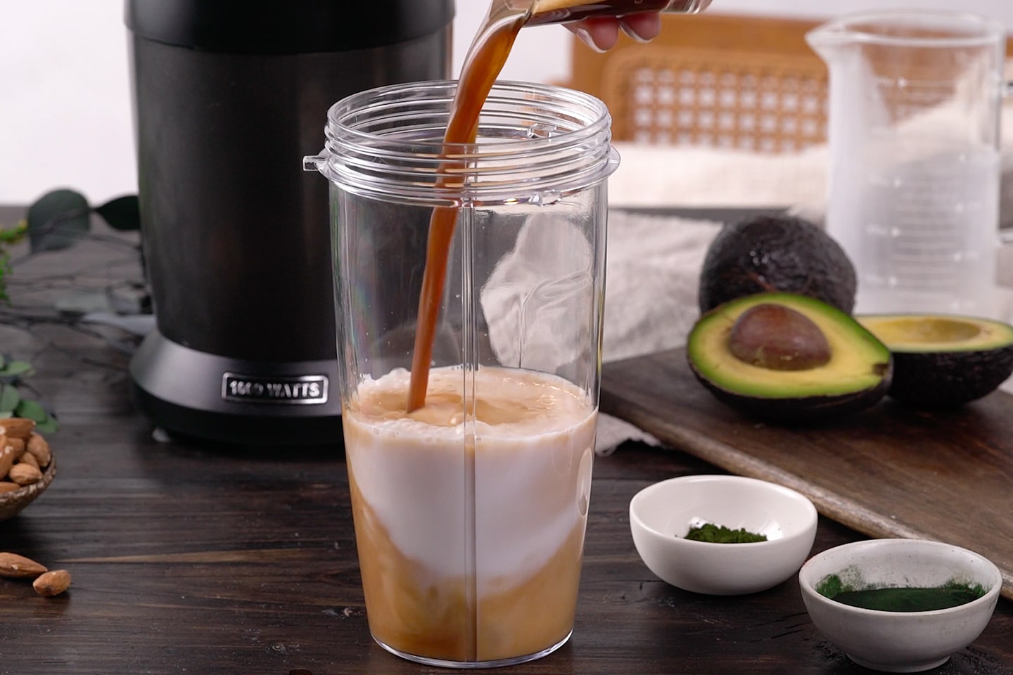 Für den grünen Kaffee-Smoothie mit Superfoods Spirulina, Chlorella und Avocado wird Kaffee zur Kokosmilch gegossen